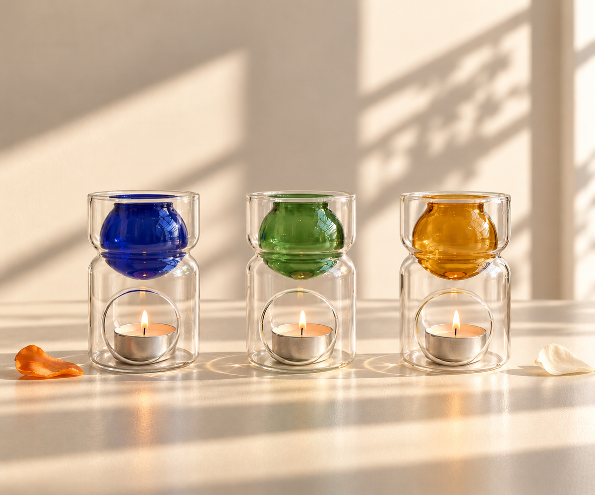 Glass oil diffusers in cobalt, green, and amber with lit tealight candles